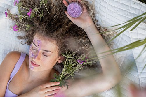 eminence-facial Girl outdoors holding flowers and wearing the Eminence facial mask