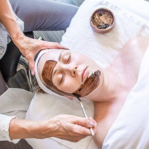 Esthetician applying a healing mask to client during facial